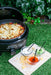 Cadac Citi Chef 40 Black - Urban & Camping Gas BBQ feature lifestyle image of BBQ on grass with nachos in and sauces on chopping board 
